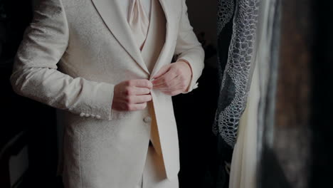 hombre en un traje beige ajustando su chaqueta, preparándose para un evento formal