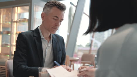 a business man has a meeting with an unrecognizable woman in a cafeteria