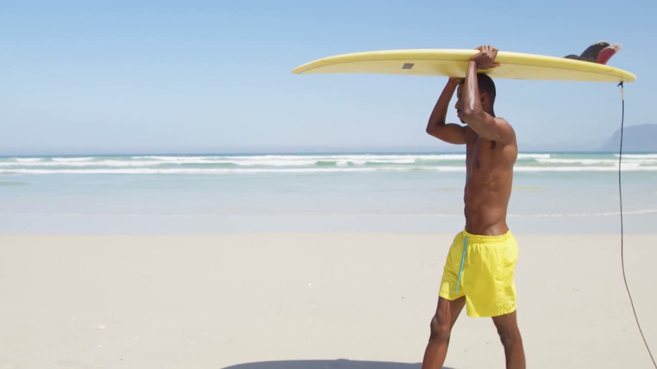 Surfista uomo che porta la tavola da surf sulla testa in spiaggia 4K
