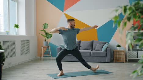 man performing yoga warrior pose at home
