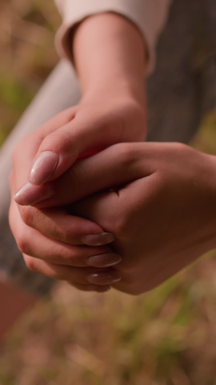 primer plano de manos individuales juntas en una postura tranquila y reflexiva, descansando de rodillas con el fondo suave del follaje de otoño en el suelo