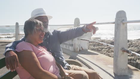 feliz pareja de ancianos afroamericanos sentados en un banco en el paseo marítimo, cámara lenta