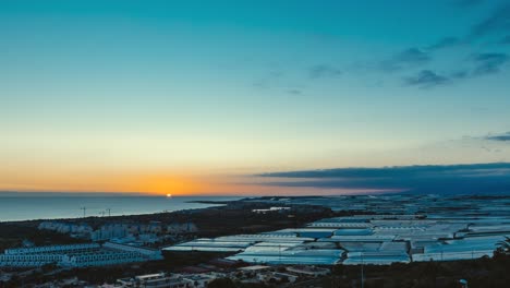sunset over coastal city with greenhouses