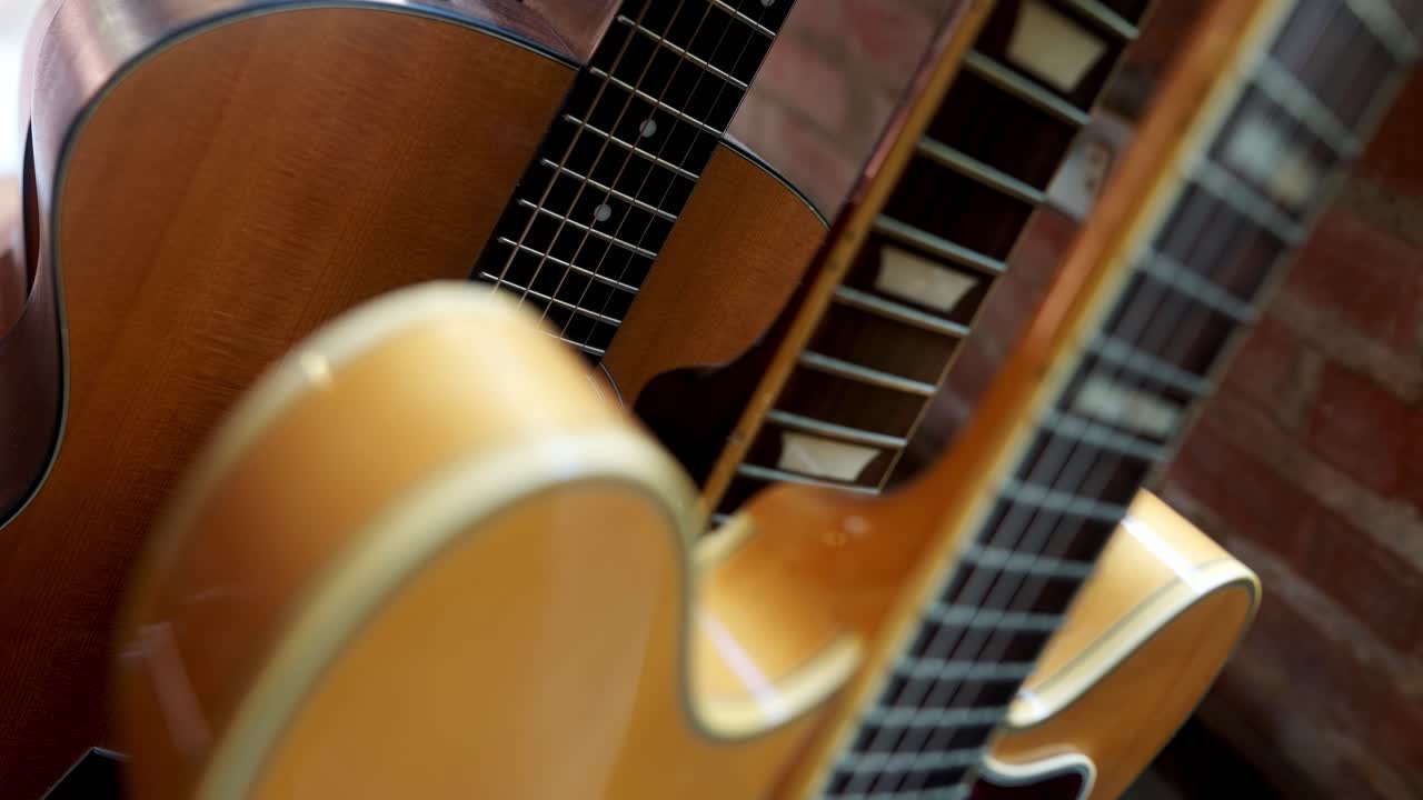 Close up view of the necks of acoustic and electric guitars in a home audio production studio.