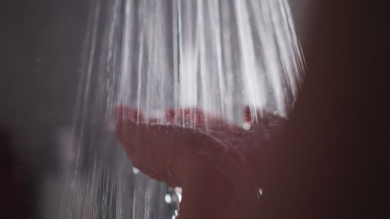 mujer sostiene las manos bajo los chorros de ducha en el baño en primer plano. dama disfruta de un fuerte flujo de agua lavando el cuerpo en el baño. mujer se lava las manos en casa