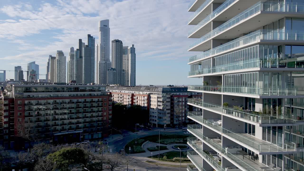High-rise apartment buildings in a modern residential area with skyscrapers in the background. Aerial reveal shot