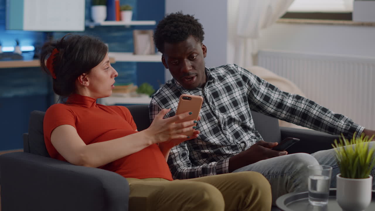Interracial couple expecting child sitting in living room