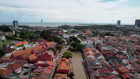 Drones-Toma-Una-Foto-En-Movimiento-Hacia-Adelante-Del-Río-Malaca-Que-Fluye-En-La-Ciudad-De-Malaca-En-Malasia,-Que-Está-Rodeada-De-Numerosos-Edificios