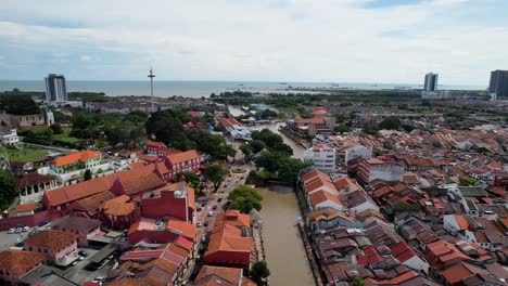 drones takes a forward moving shot of the river malacca flowing in the city of malacca in malaysia which is surrounded by numerous buildings