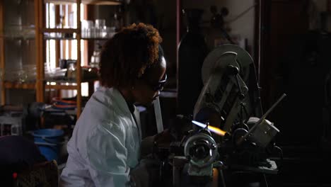 Side-view-of-black-female-worker-blowing-glass-in-glass-factory-4k