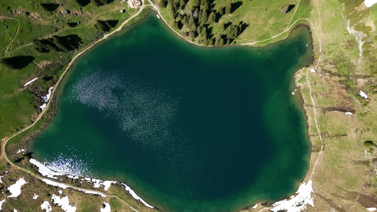 Top down drone shot of Lake Lioson during the day with snow and restaurant in Ormont-Dessous, near Les Mosses, in the canton of Vaud, Switzerland
