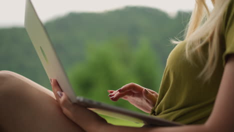 woman holds laptop and adjusts hair lock at eco resort