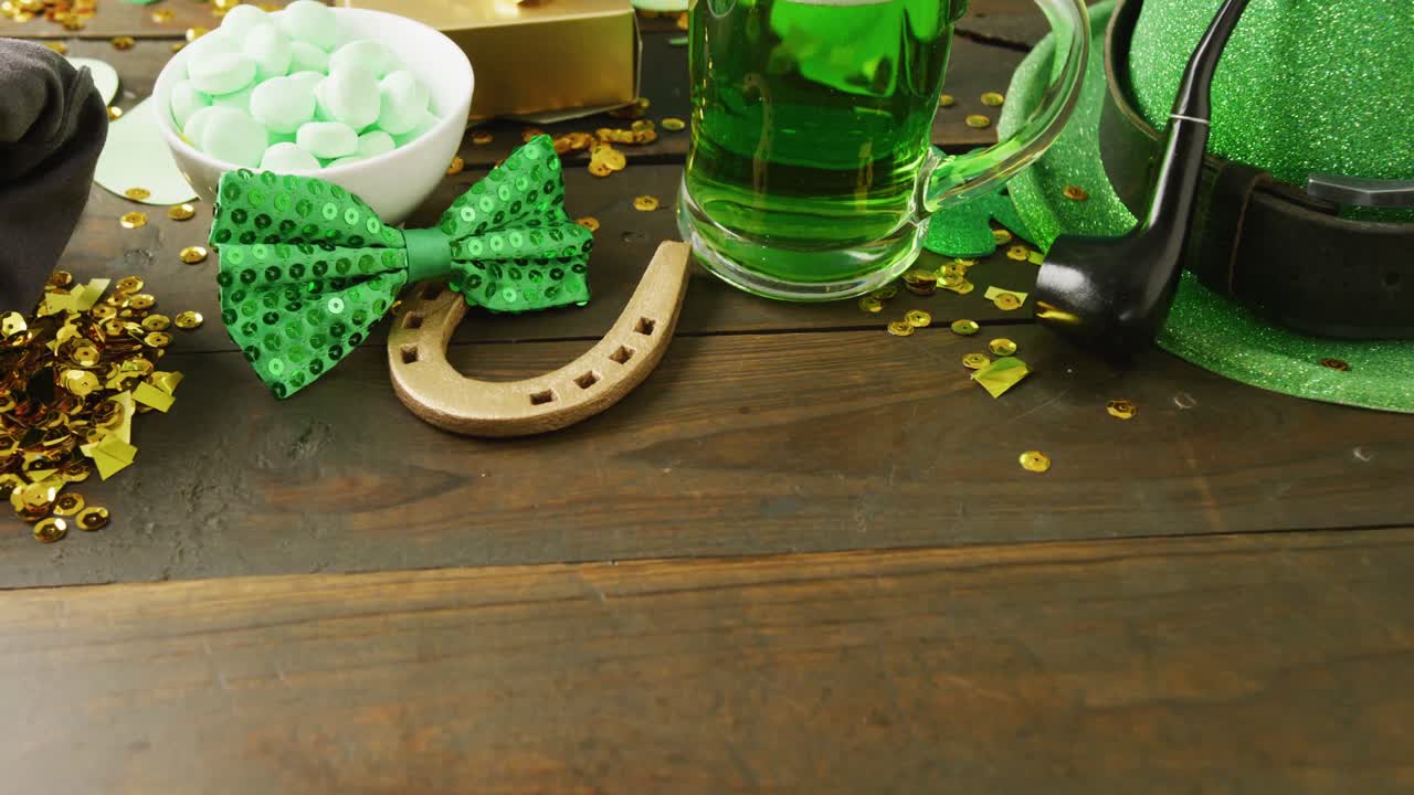Video of st patrick's hat, beer, bow tie and horseshoe with copy space on wooden background