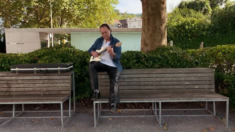 ein gitarrist setzte sich auf eine bank und spielte gitarre