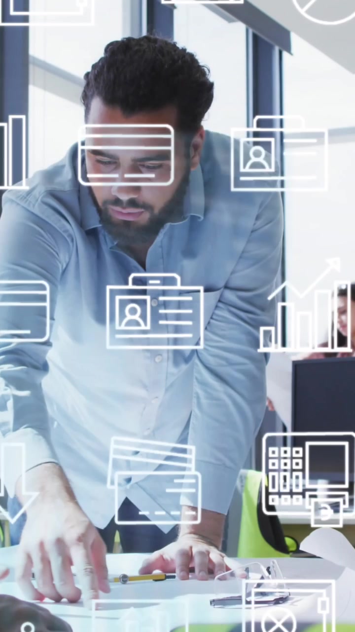 Animation of multiple icons over diverse male architects discussing blueprint in office