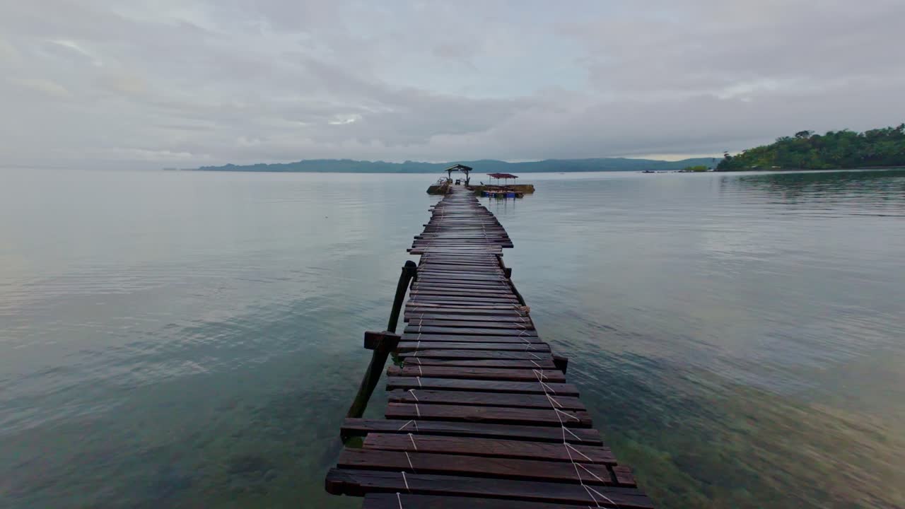 Rustic wooden dock leads out over calm water on Dinagat Island, Philippines