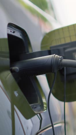 vertical video closeup of electric car charging port cover opened to recharge depleted battery,