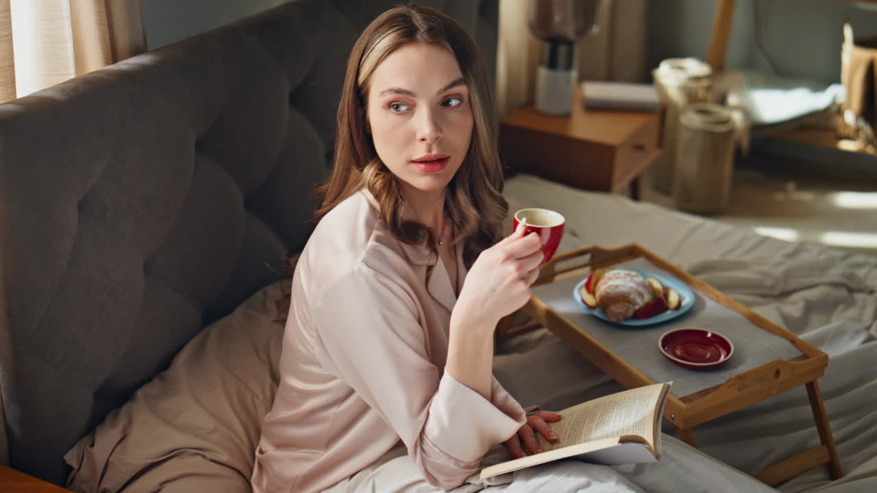 Donna che si gusta la colazione e legge a letto