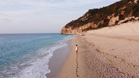 Mujer-Deja-Huellas-Durante-El-Paseo-Por-La-Playa-En-La-Playa-De-Milos,-Isla-De-Lefkada,-Grecia---Muñeca-Aérea