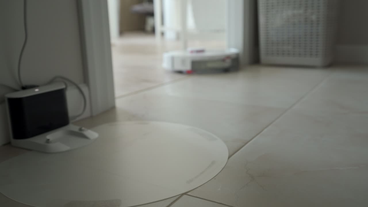 White robot vacuum cleaner performs automatic cleaning of the apartment, modern technology of smart cleaning.