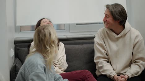 Two-women-and-man-having-fun-together-at-home-while-taking-pizza