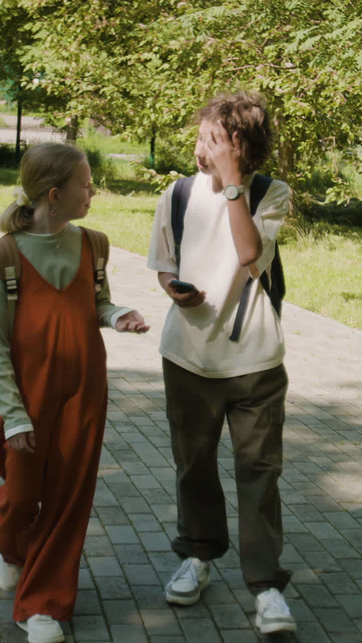 Two Children Walking and Talking in a Sunny Park