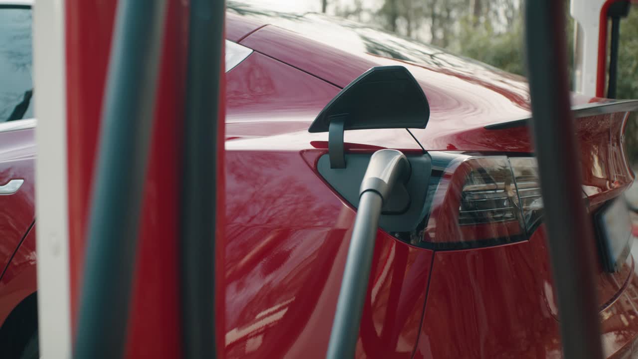 The red electric car is being charged at the charging station