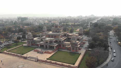 Majestuoso-Museo-Albert-Hall-En-El-Centro-De-Jaipur,-Rodeado-Por-Un-Intenso-Tráfico-Indio,-En-Rajasthan,-India---Toma-Panorámica-Aérea-En-órbita