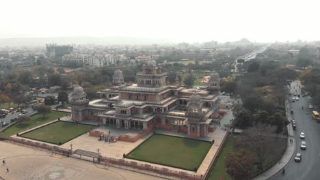 majestuoso museo albert hall en el centro de jaipur, rodeado por un intenso tráfico indio, en rajasthan, india - toma panorámica aérea en órbita