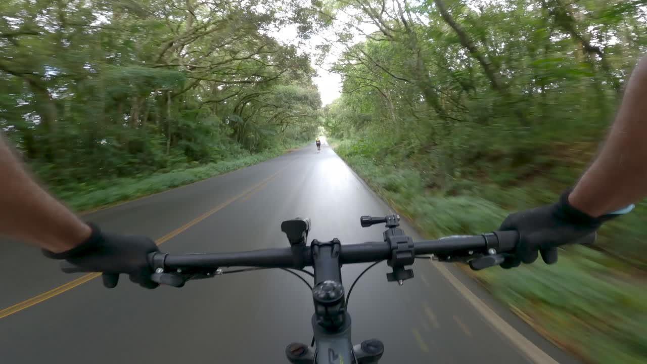 ciclistas pasando por una carretera de campo boscosa después de la lluvia, video pov
