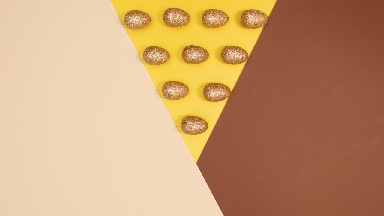 huevos de glamour dorado de pascua girando sobre un fondo desnudo dorado de tres colores. parada de movimiento patrón de colocación plana