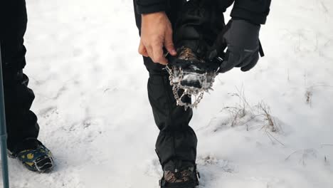 a hiker trying to put crampon on his winter boots
