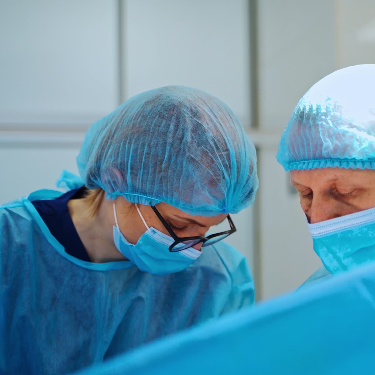 Surgeon and female assistant in masks. Professional doctor together with a nurse doing an operation on a patient in clinic.