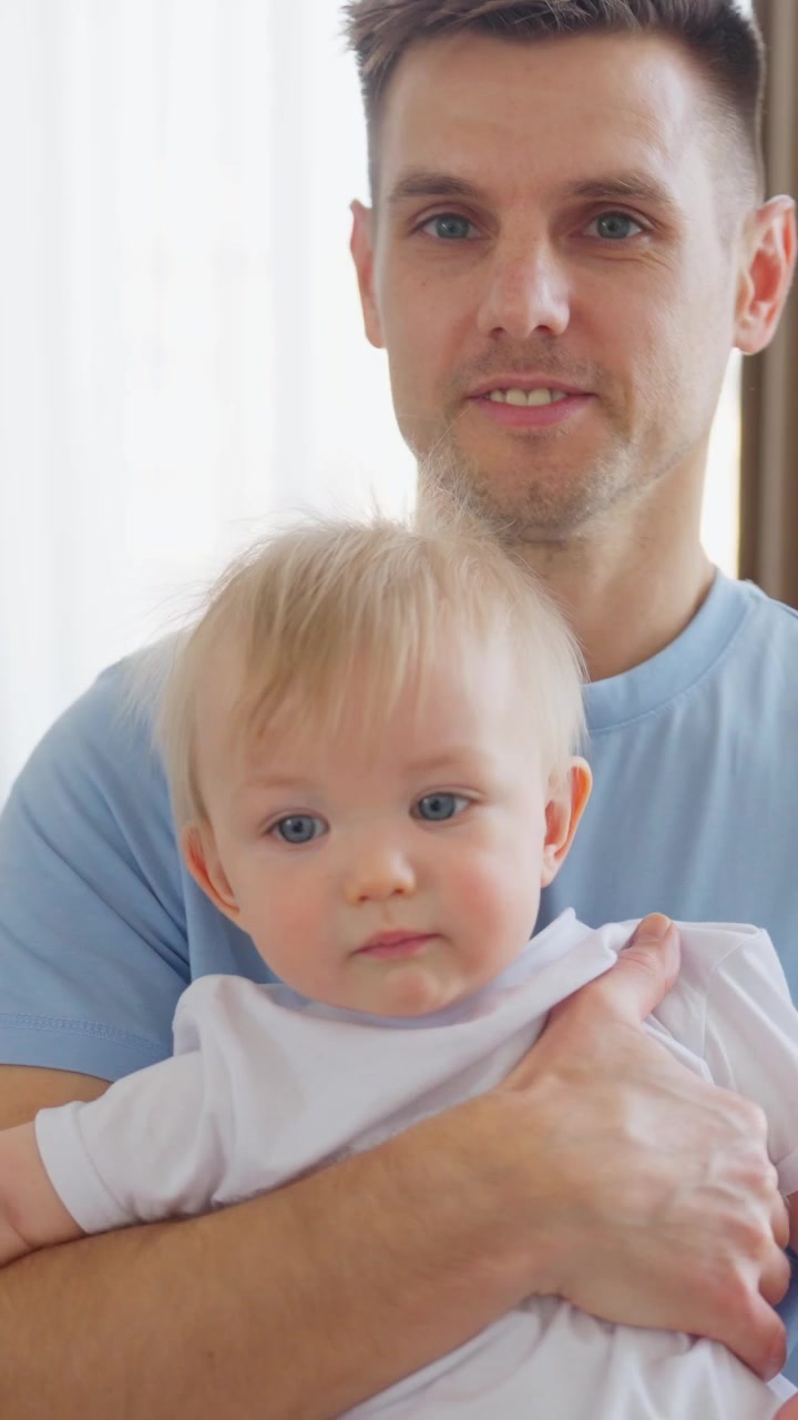 Padre sorridente che tiene in braccio il suo adorabile bambino con gli occhi azzurri