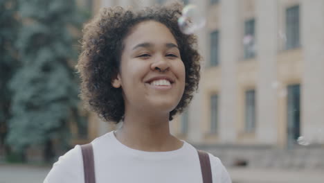 teenage girl blowing bubbles outside