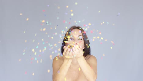 Young-woman-blowing-colorful-New-Year-confetti