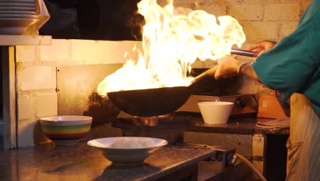 chef flaming food on wok in traditional vietnamese restaurant, close up