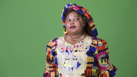 overweight beautiful african woman wearing traditional clothing against green background