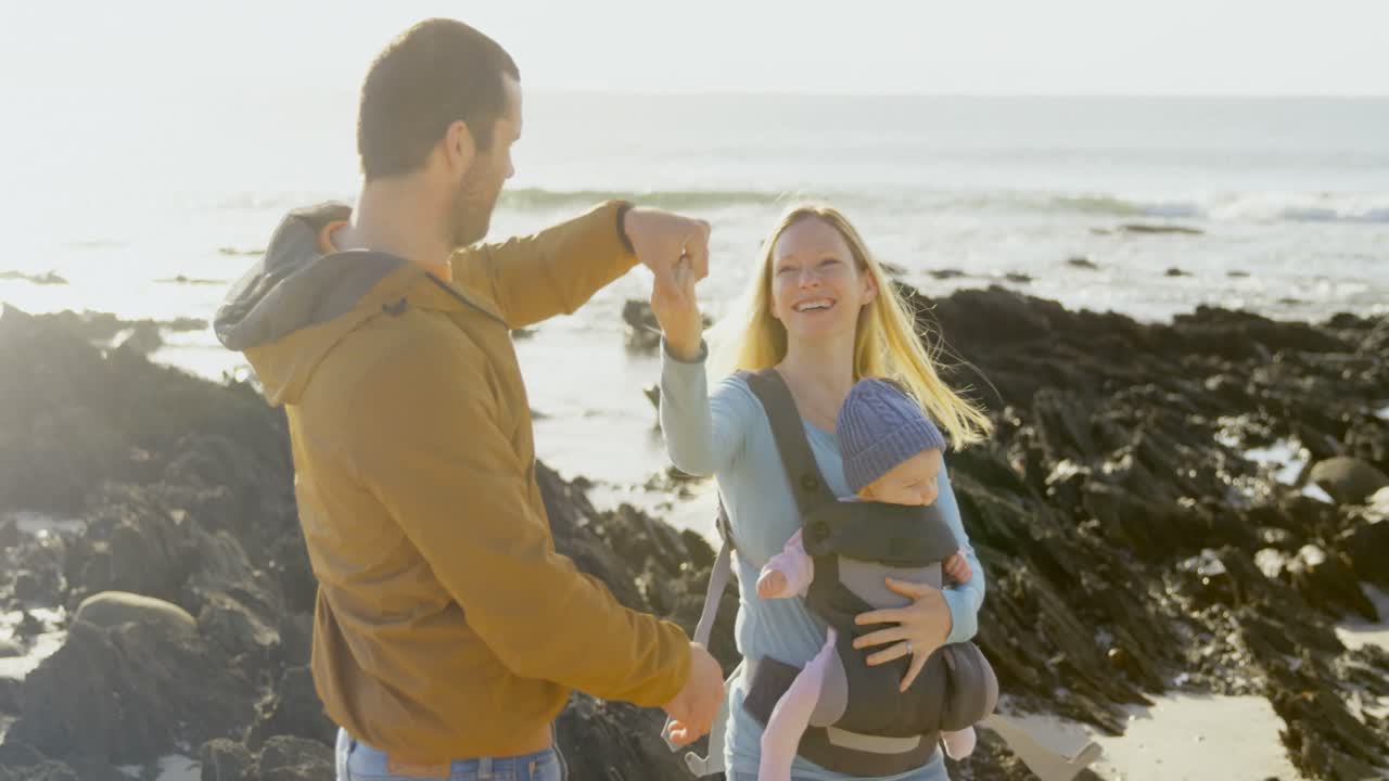 vista lateral de una feliz familia caucásica bailando en la playa en un día soleado 4k