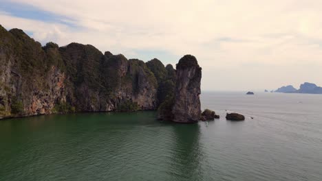 Breathtaking-view-of-a-secluded-bay-with-turquoise-water,-surrounded-by-towering-cliffs-covered-in-lush-green-vegetation