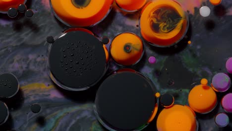 Top-view-movement-of-black-orange-oil-ink-drops-bubbles,-multicolored-artistic-paint-background