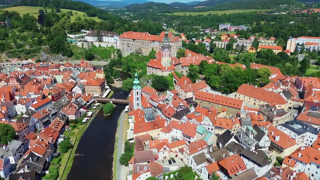 A slow flying down shot over a historic city centre. There are a bunch of old buildings and a castle in the middle. It's a sunny day with some clouds