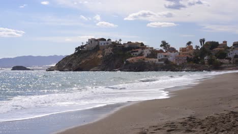 Orilla-Del-Mar-Arenosa-Con-Olas-En-Un-Día-Soleado