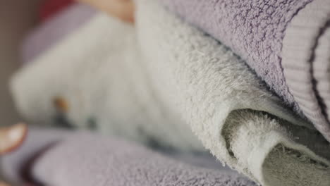 Women&#039;s fingers sort through clean towels on a shelf in the closet