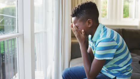 Un-Niño-Afroamericano-Estresado-Mirando-Por-La-Ventana-Mientras-Estaba-Sentado-En-El-Sofá-De-Casa