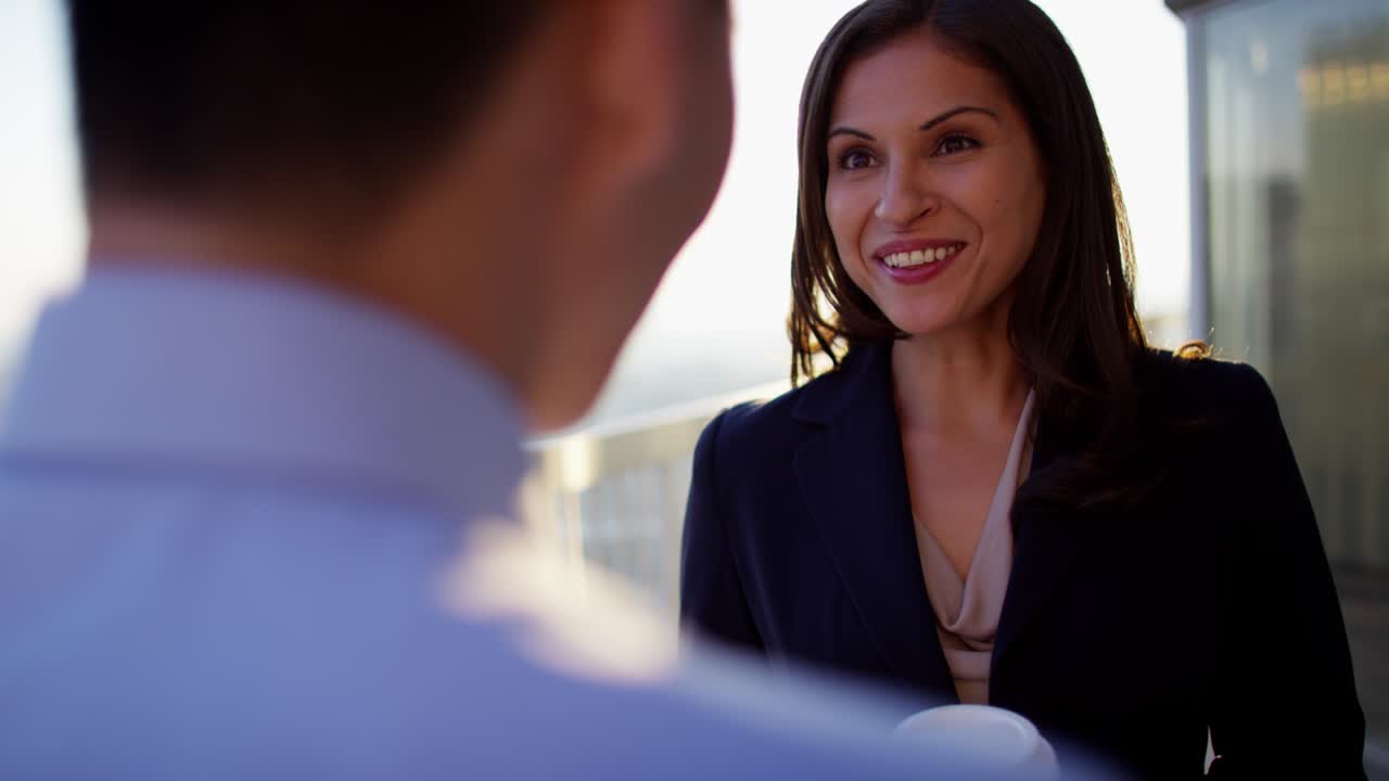 una mujer hispana y un hombre asiático bebiendo café.