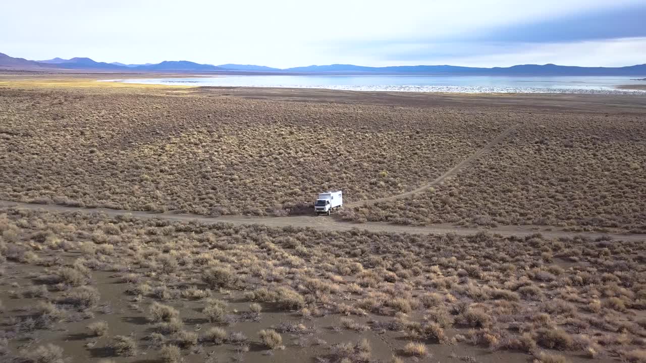 drone alejándose mostrando un desierto, montañas y un lago mono