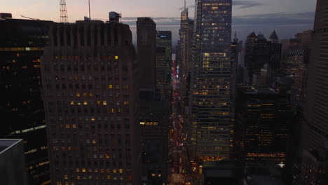 Forwards-fly-high-above-busy-street-between-modern-high-rise-downtown-buildings.-City-at-dusk.-Manhattan,-New-York-City,-USA