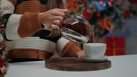 Close-up-of-woman-pouring-tea-from-kettle-in-cup