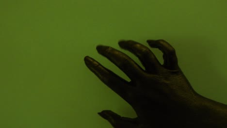 young female hand painted with black color moving smoothly in a green background